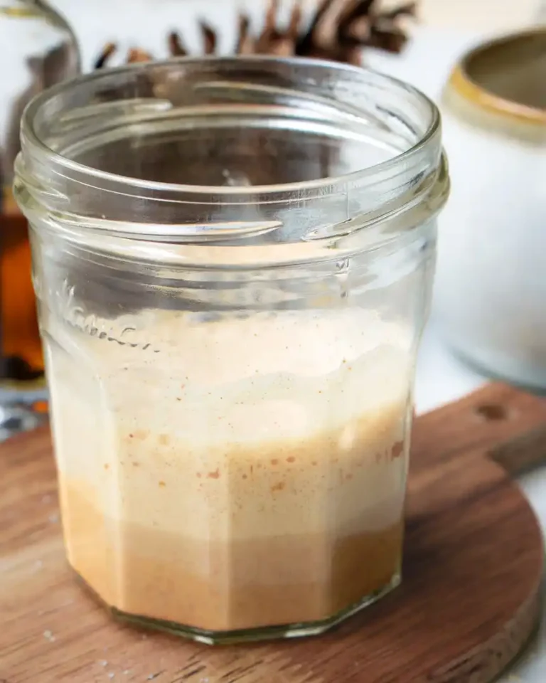 A small glass jar filled with frothed milk and spices.