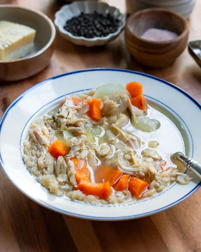 A bowl of chicken soup with a spoon in it.