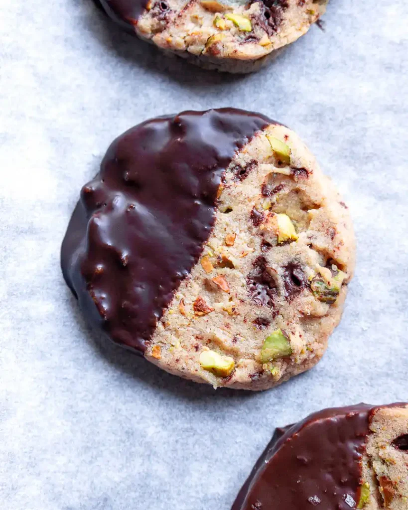 A gluten-free dark chocolate pistachio cookie on a baking sheet.