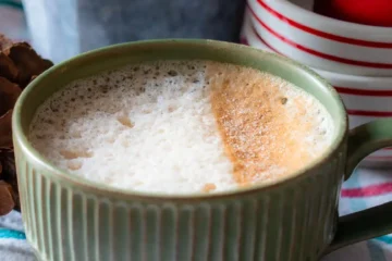 A mug of gingerbread latte. One side of the milk is dusted with cinnamon sugar.