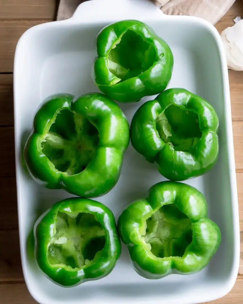 Hollowed out bell peppers in a baking pan.