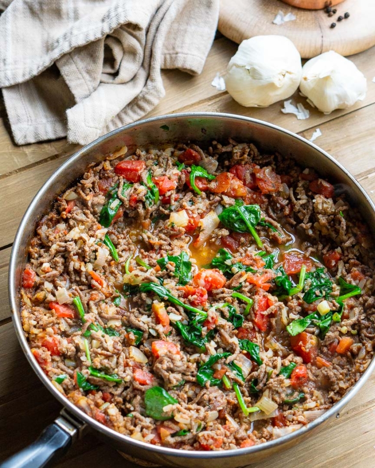 A skillet with ground beef and tomato filling.