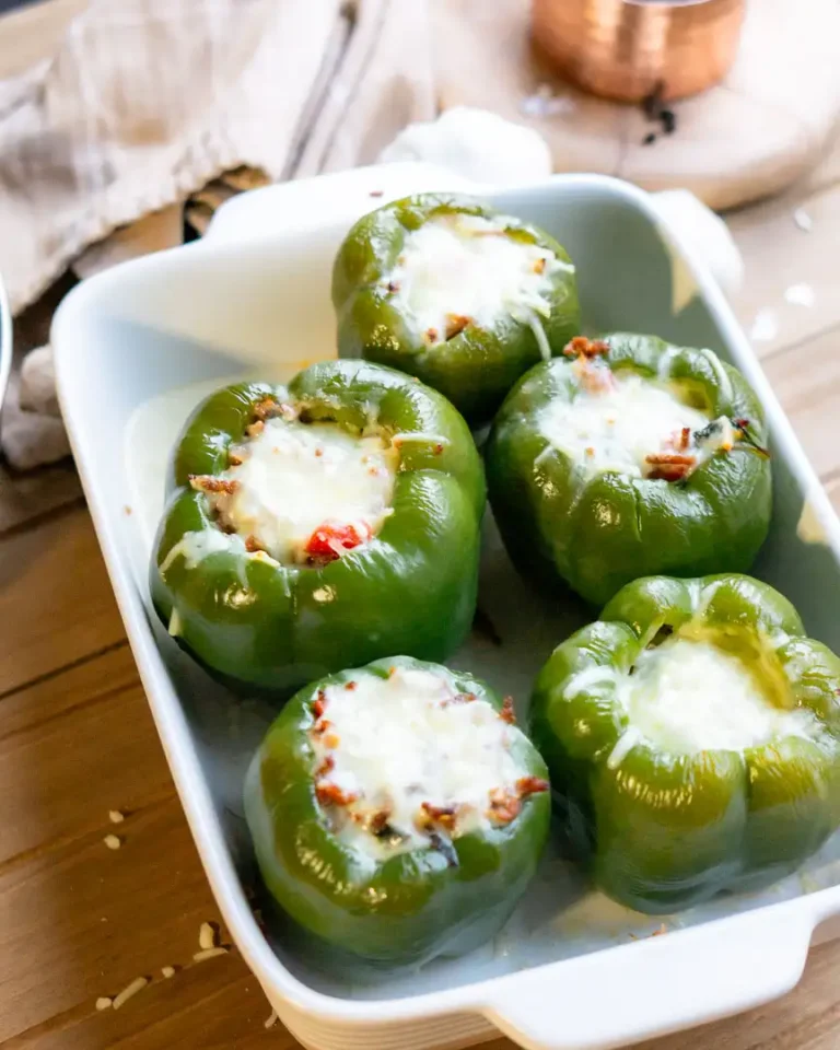 A baking pan of 5 stuffed peppers with melted mozzarella cheese on top of each pepper.